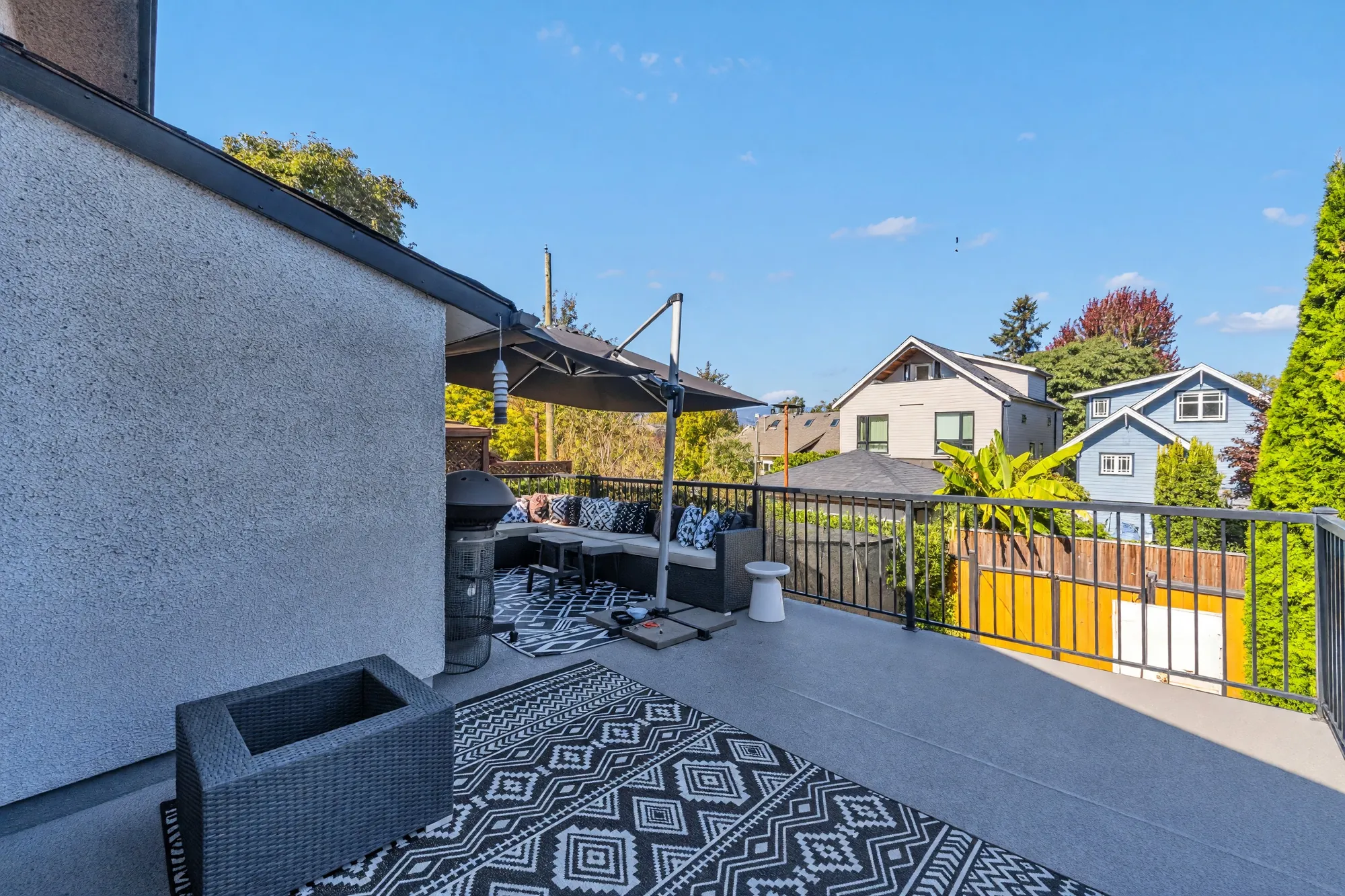 The balcony from the chimney end: the deck, the umbrella, the railing, the houses across the lane