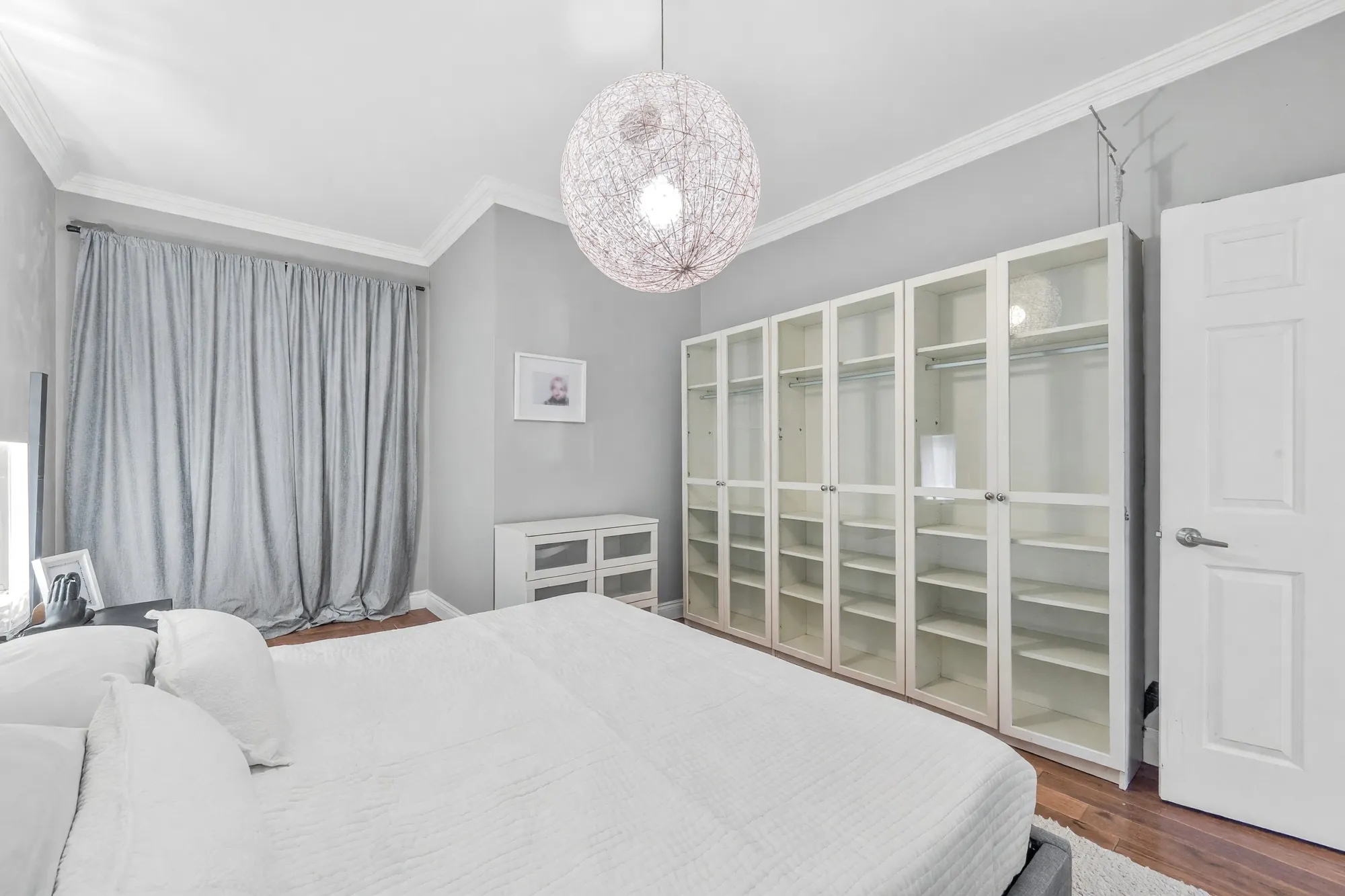 The same bedroom toward its glass-door wardrobe and the door, the pendant above the bed
