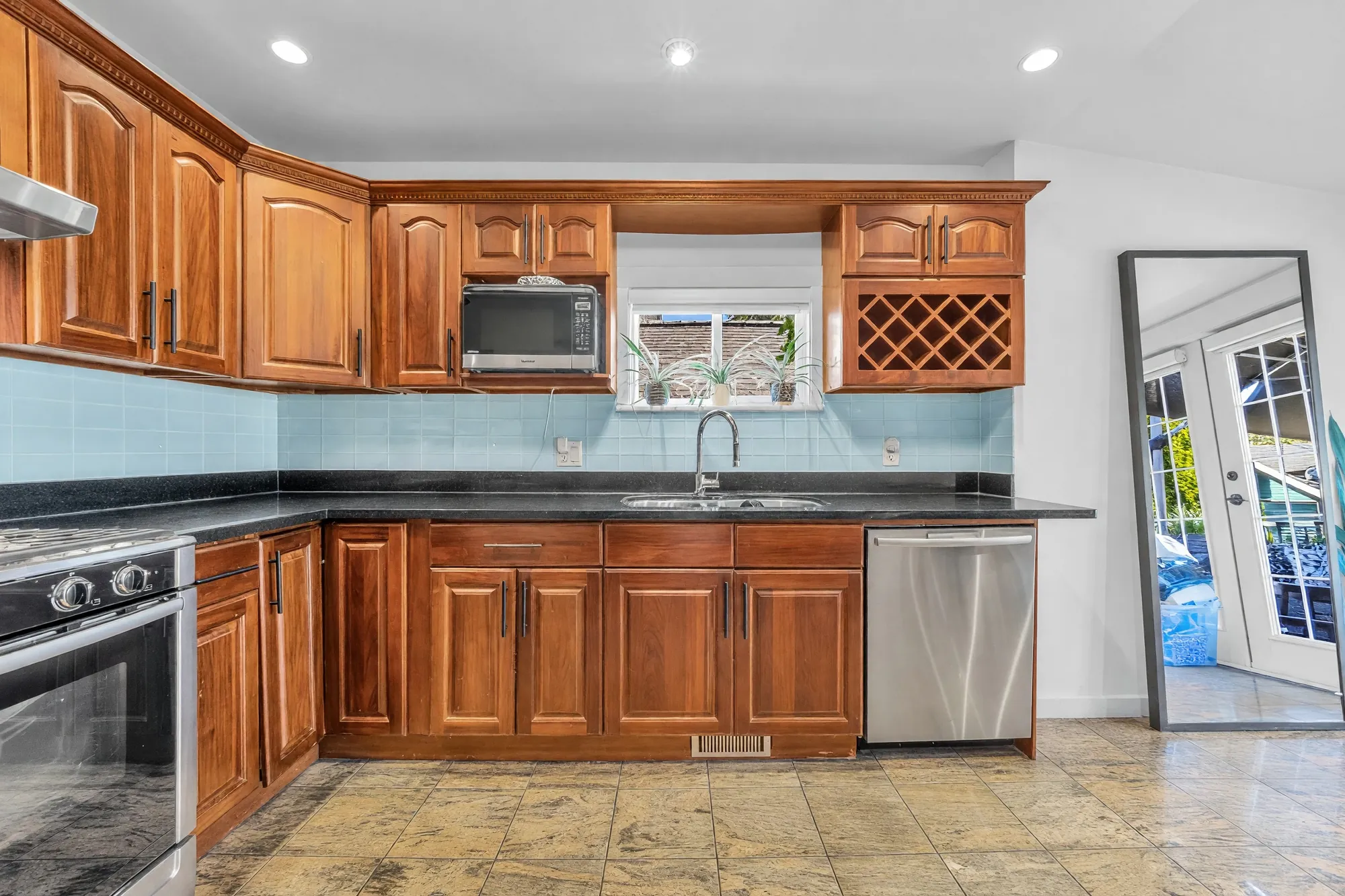 The kitchen toward the French doors, the sink under the window, a tall mirror by the doors