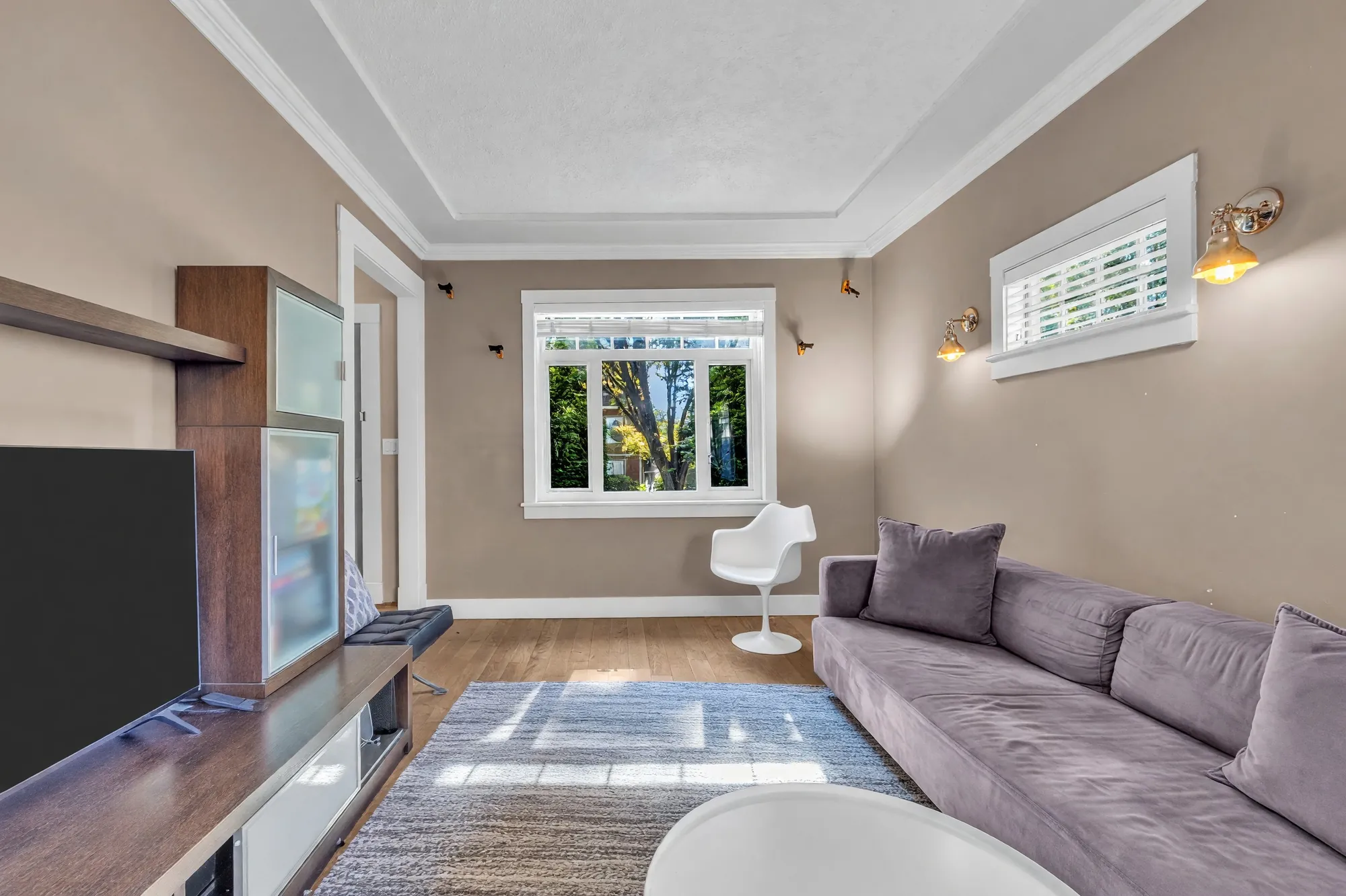 Down the room from the television wall: the sectional, the front window, sconces on the walls