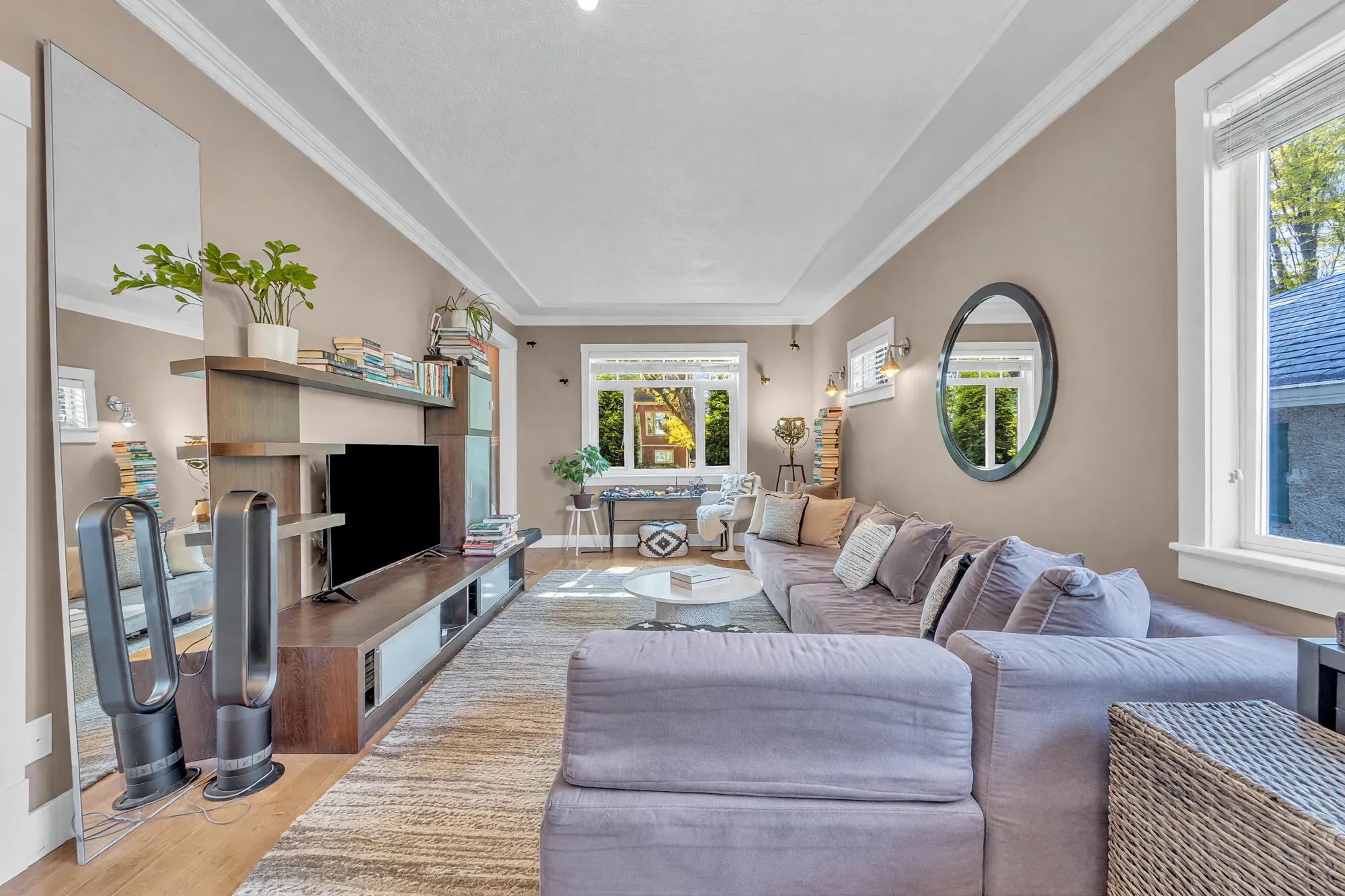 The length of the room from the front: the television unit, the sectional, the mirror and the windows