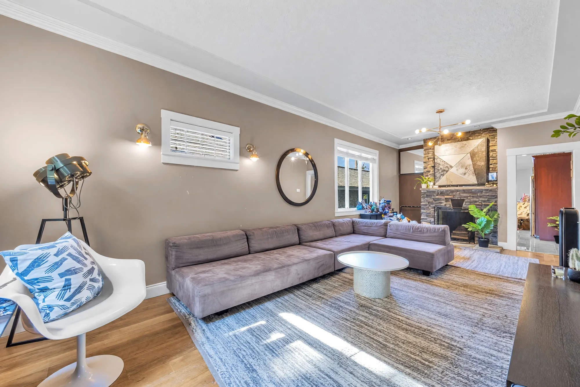 From the front window: the sectional, a round white table, the fireplace at the far end, a white chair