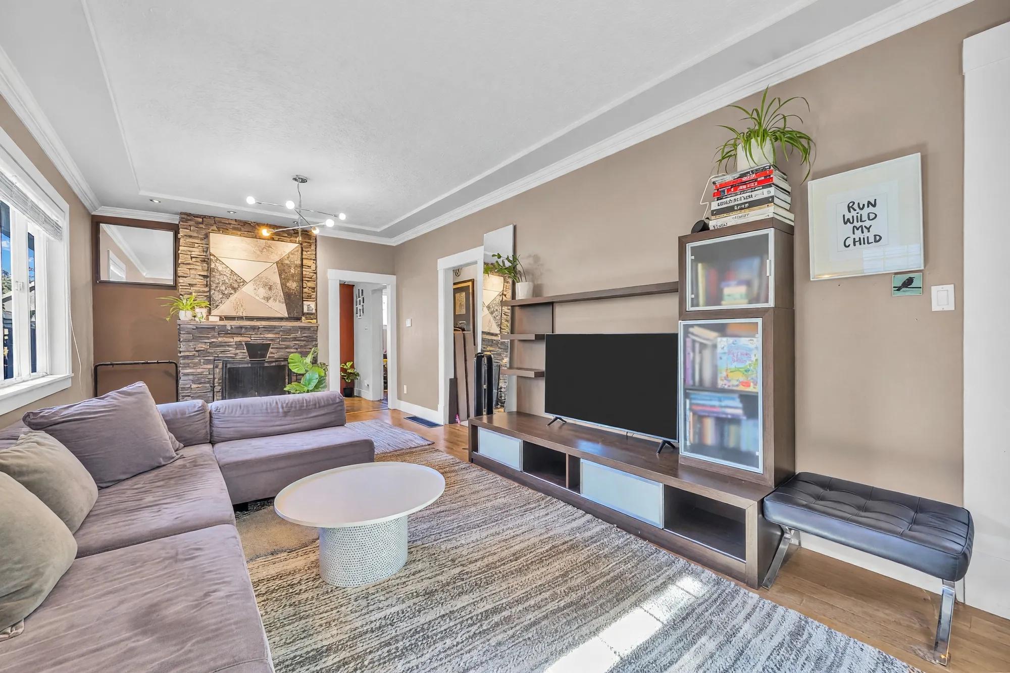 The television unit and a bench under a print, the fireplace and the kitchen doorway beyond